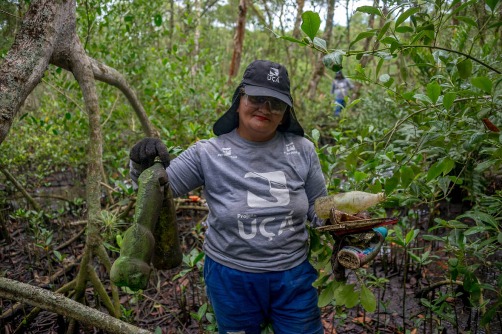 Mulher exibe garrafas pet coletadas no mangue - Projeto Uçá